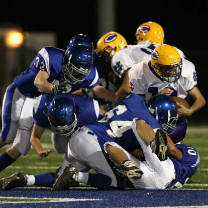 Amador Gaspar (64), Tanner Rich (70) and Jason Browning (32) help bring down Catholic running back Alex Meyers. (Photo by Rick Nation)