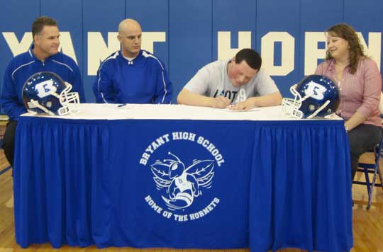 Kaleb Burns signs his letter of intent to attend Sterling College as, from left, Bryant head coach and offensive line coach Paul Calley, offensive coordinator Dale Jones and Kaleb's mother Sandee look on.