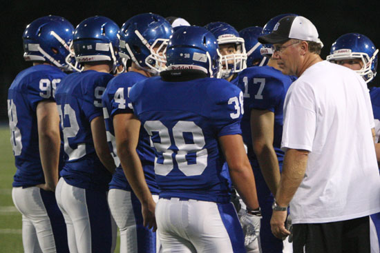 Defensive coordinator Steve Griffith huddles up with a group of Bryant defenders. (Photo by Rick Nation)