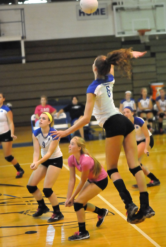 Allie Anderson leaps high for a hit as teammates Kendall Selig, Whitney Brown and Britney Sahlmann get into position. (Photo by Kevin Nagle)